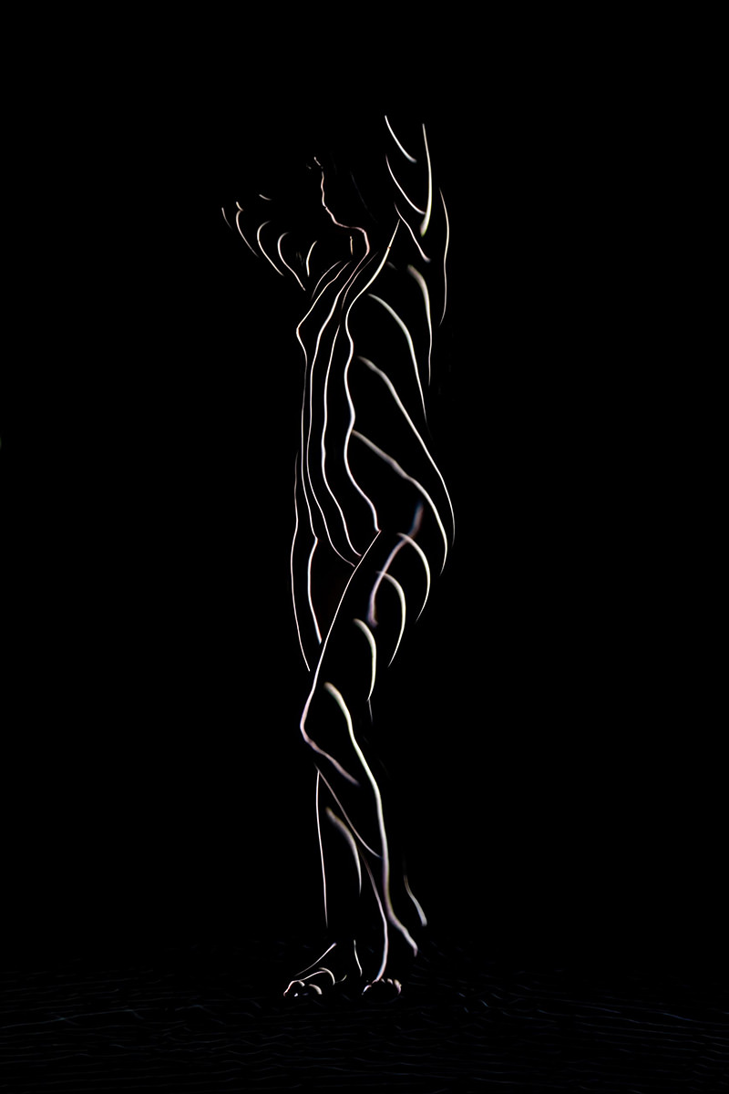Silhouette of a nude person outlined by glowing, curved light lines creating an abstract, artistic effect against a black background