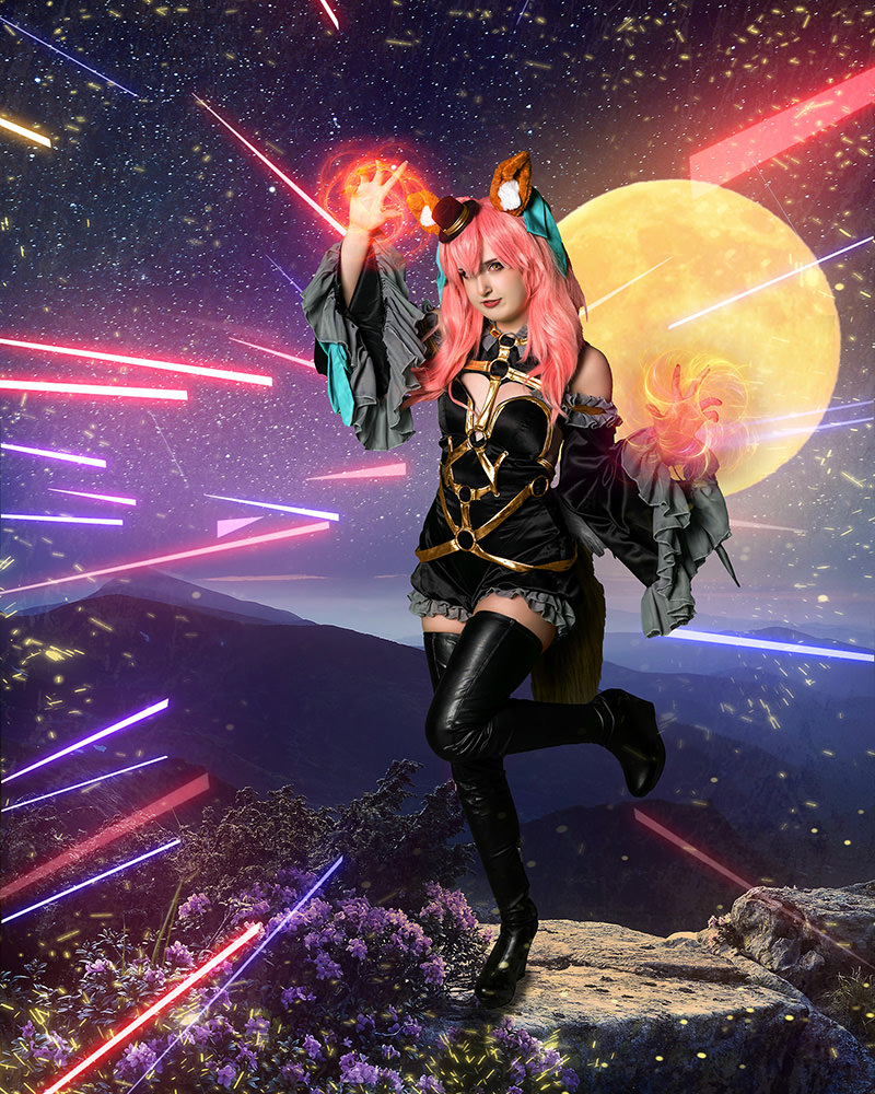 A person in a detailed cosplay outfit with pink hair and fox ears, standing on a rock surrounded by purple flowers, extends hands emitting glowing magical energy, with a large yellow full moon and colorful light streaks in the starry night sky.
