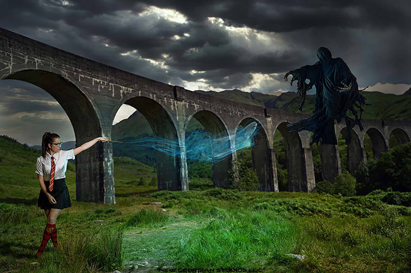 Young woman in school uniform casting a glowing blue spell from her wand towards a dark, hooded floating figure under a stone arch bridge in a green, cloudy landscape